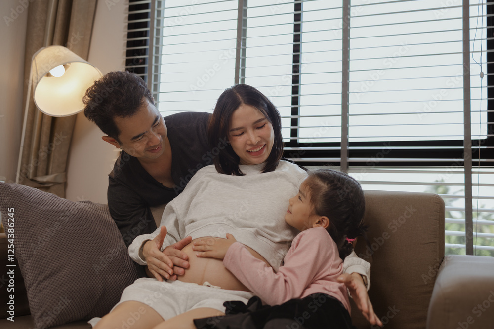 lovely family spend time together in their house, a pregnant mother sits on the couch with her husband and daughter enjoying a happy time together on a weekend lovely family spend time together in their house, a pregnant mother sits on the couch with her husband and daughter enjoying a happy time together on a weekend