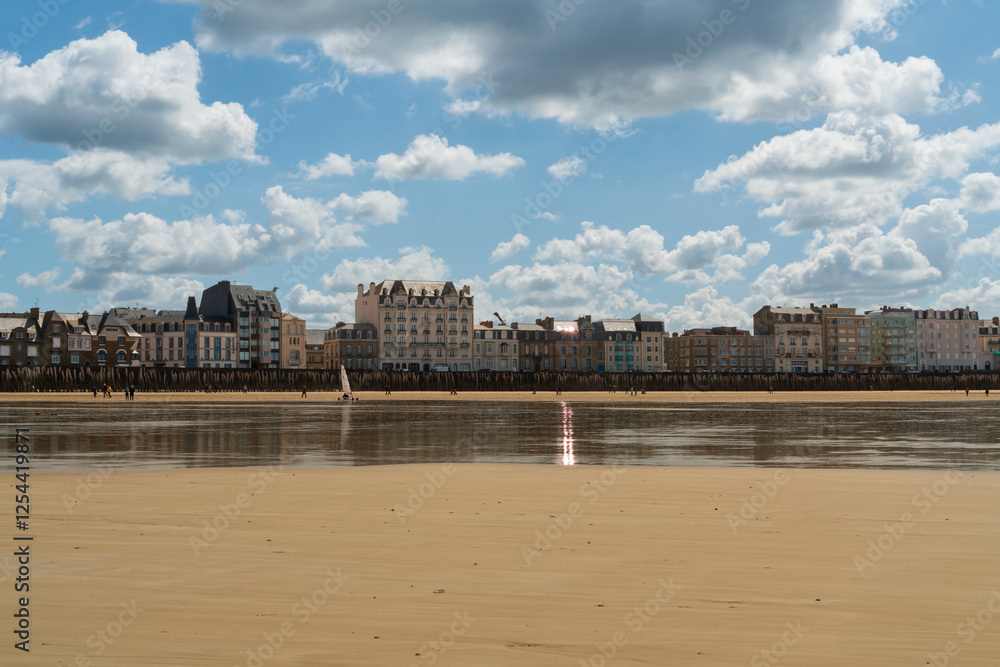 Fototapeta premium View of the promenade and the beach with wooden breakwaters at low tide on a sunny summer day, Saint-Malo, Brittany, France
