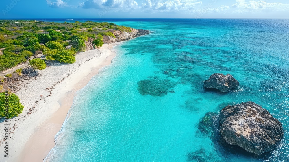 Obraz premium Aerial view of a serene tropical beach with turquoise waters and rocky formations under a clear sky