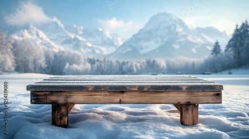 Wooden bench covered in snow with snowy mountain range background.