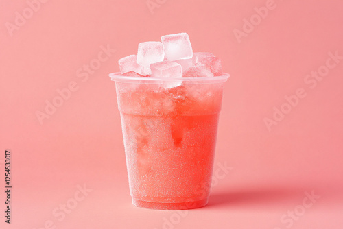 Refreshing drink served in a clear cup, filled with ice cubes against a soft pink background.