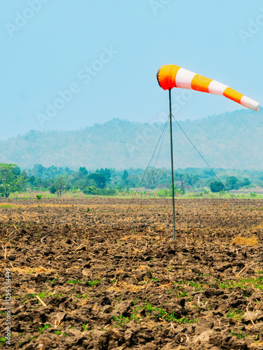 Windsock indicator of wind in meadow with beautiful scenic. Flying windsock or wind vane in field. meteorology. Airport windsock. Air field direction sign , Air sock, Drogue, Wind sleeve, Wind cone.
