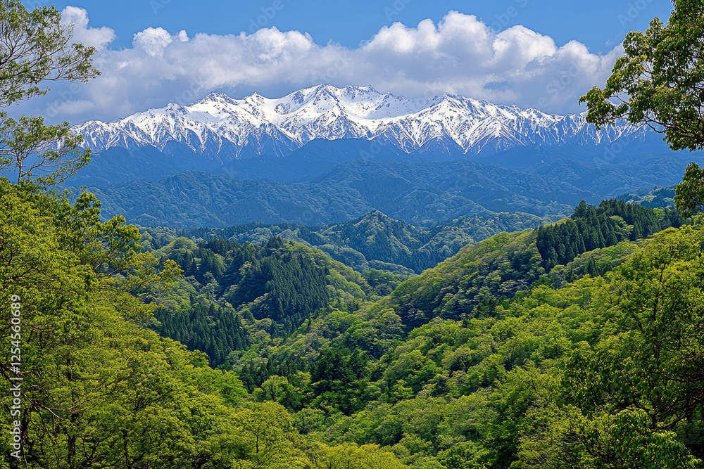 Fototapeta premium Majestic snow-capped mountain peaks with lush green forest and layered hills under clear blue sky