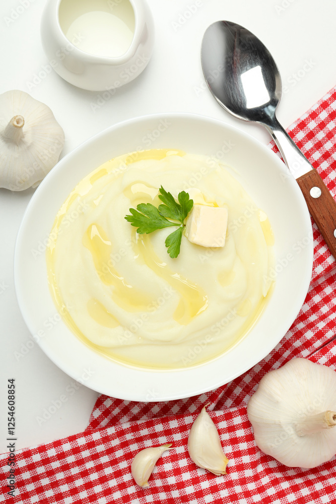 Mashed potatoes in bowl on towel, spoon and garlic on white background, top view Mashed potatoes in bowl on towel, spoon and garlic on white background, top view