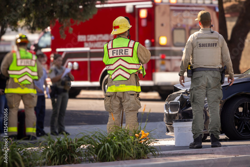 A police officer and a firefighter standing next to each other at a car accident scene