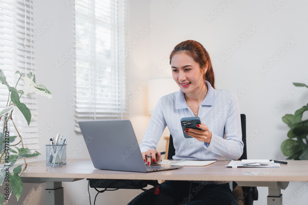 Woman working at desk with laptop and smartphone, smiling in bright office. Woman working at desk with laptop and smartphone, smiling in bright office.