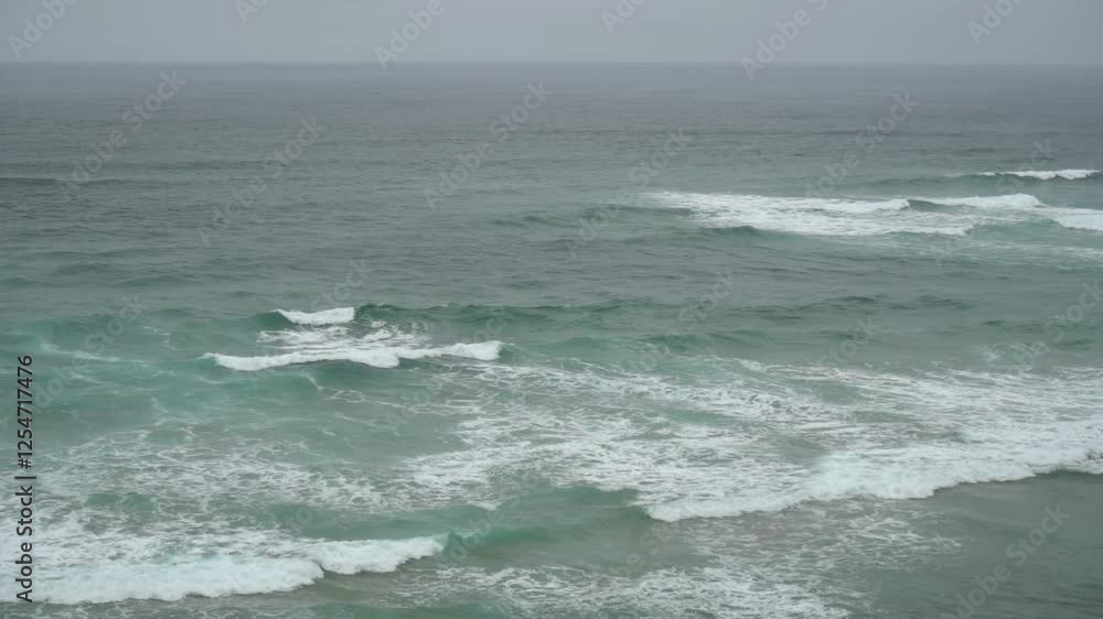 Slow motion blue rolling waves on a grey cloudy day Slow motion blue rolling waves on a grey cloudy day