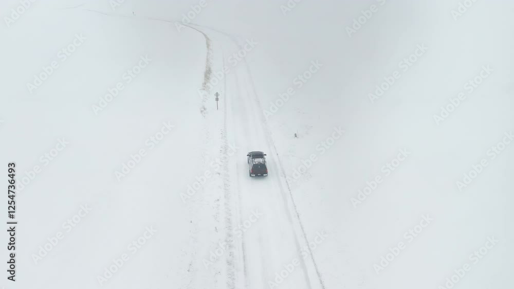 An aerial follow cam of a brown truck driving along a winding snow covered road in the country An aerial follow cam of a brown truck driving along a winding snow covered road in the country