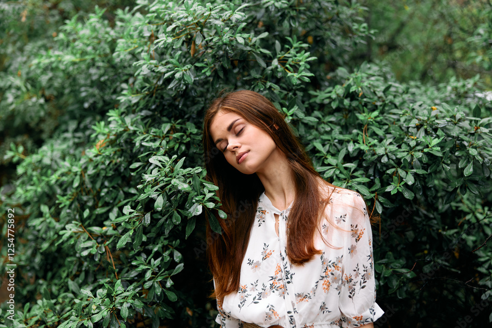 Frustrated young woman leaning against bush with eyes closed in moment of contemplation and distress Frustrated young woman leaning against bush with eyes closed in moment of contemplation and distress