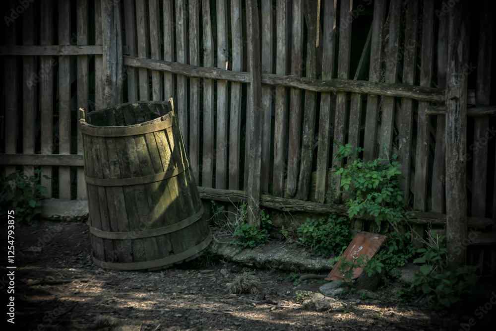 An old wooden barrel next to a wooden fence in the countryside