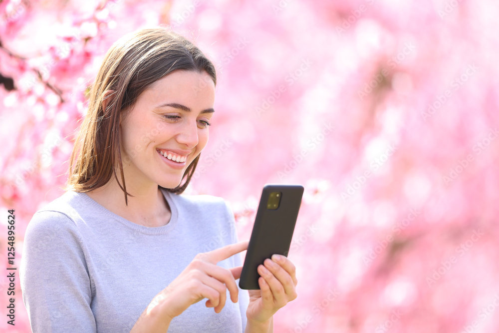 Happy woman checking smart phone in a field Happy woman checking smart phone in a field