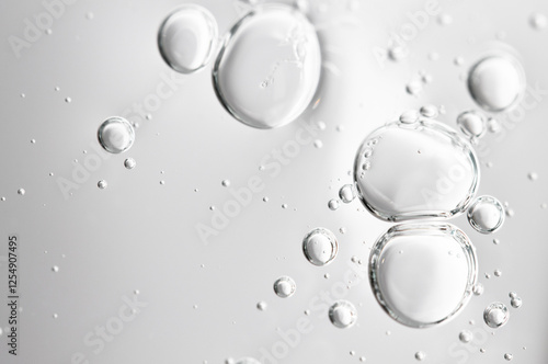 Transparent serum, hyaluronic acid with bubbles on light gray background, macro.