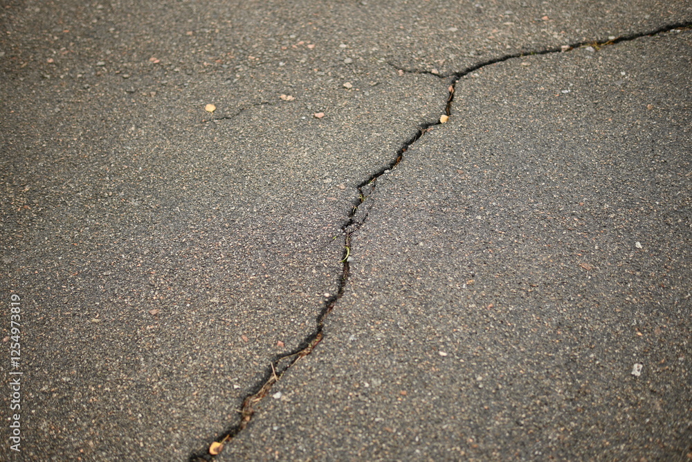 Obraz premium Cracks on grey asphalt close-up, old cracked asphalt close-up, old road surface bitumen 