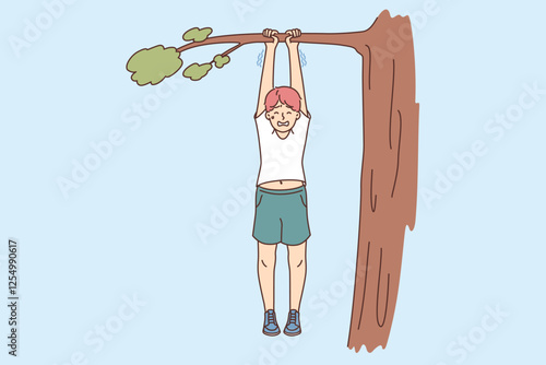 Boy risks falling from tree, hangs on branch and holds on with all strength due to carelessness