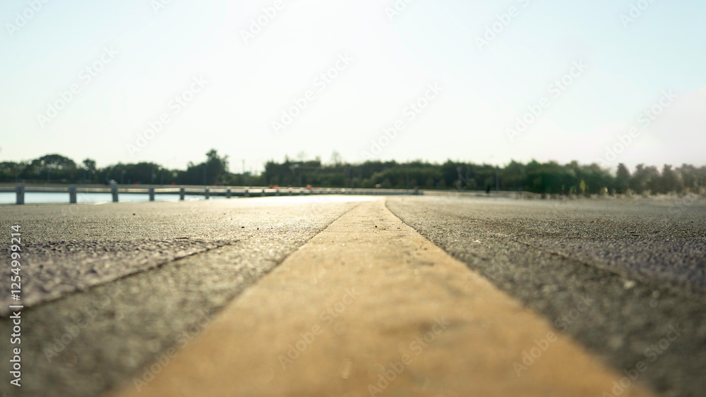 Road with a yellow line down the middle. The road is empty and the sky is clear