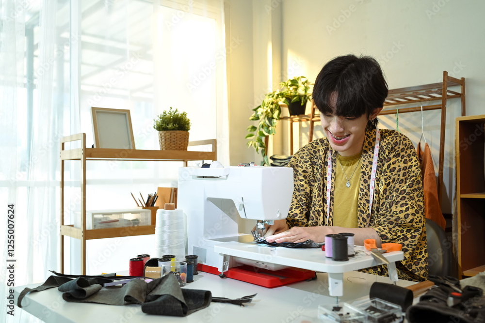 Smiling young designer working on sewing machine in a creative workspace Smiling young designer working on sewing machine in a creative workspace