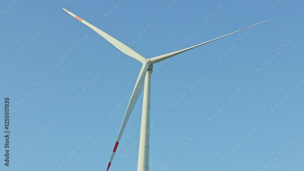 Large windmills in the field spin and produce energy. Eco energy production. Windmills on the sky background. Large windmills in the field spin and produce energy. Eco energy production. Windmills on the sky background.