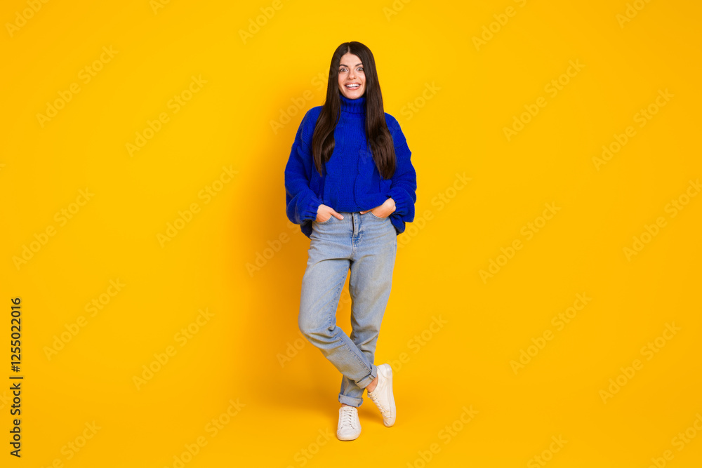 Fototapeta premium Young woman in blue sweater posing confidently against bright yellow background