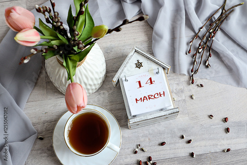 Calendar for March 14: numbers 14, name of the month March in English on a decorative calendar, cup, bouquet of tulips photo