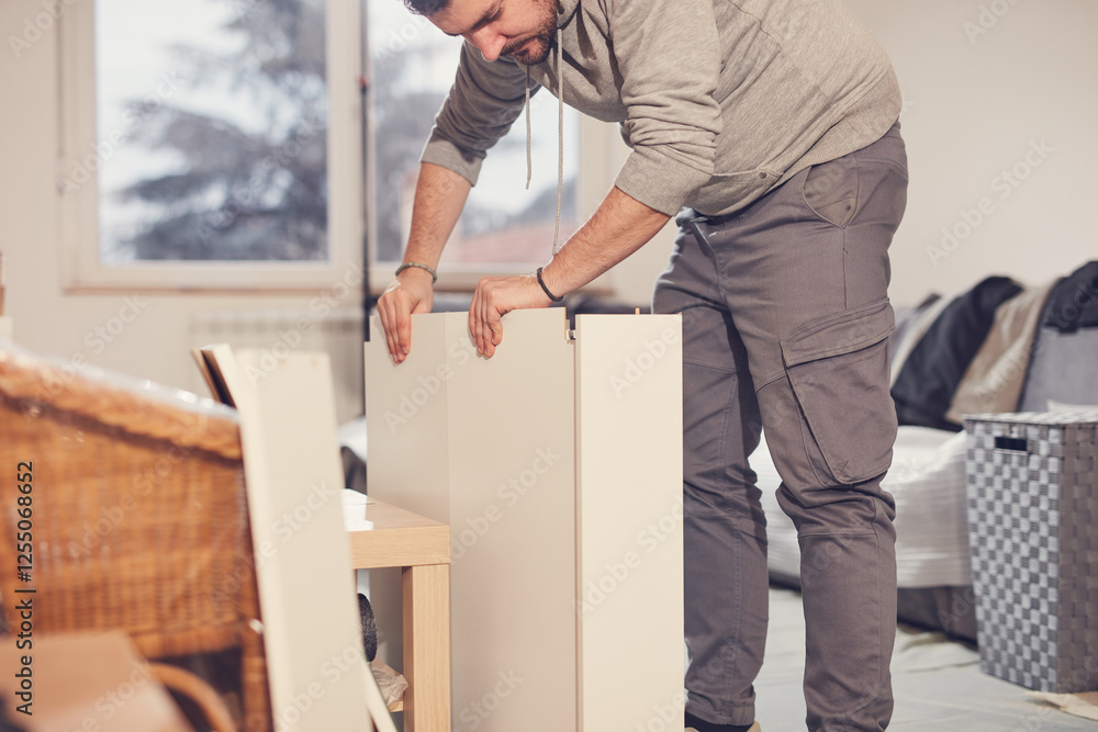 Fototapeta premium Man working and assembling furniture in a new apartment.