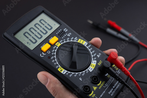 Canvastavla Hand holding a digital multimeter with test leads, on a dark background