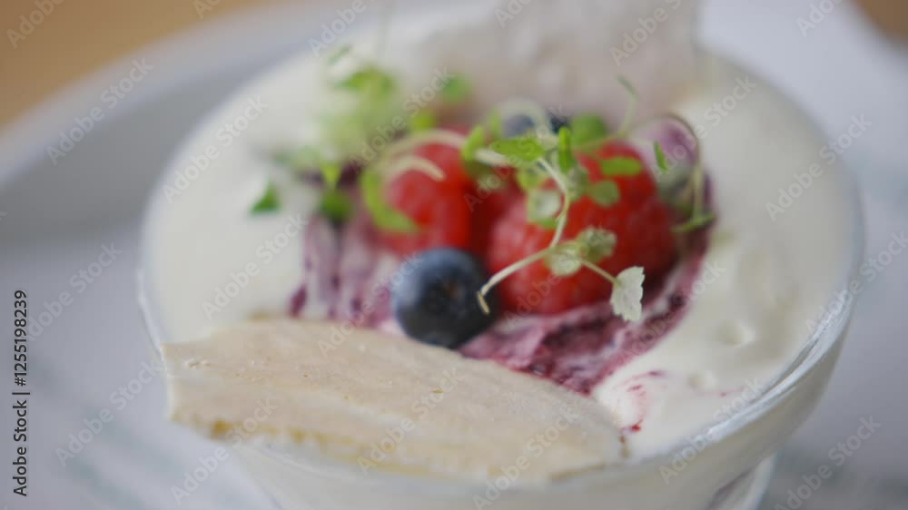 A dessert with blueberries and raspberries on top. The dessert is in a glass bowl A dessert with blueberries and raspberries on top. The dessert is in a glass bowl