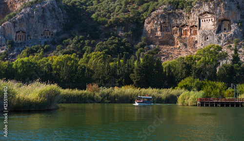 Lycian King Tombs in Kaunos Ancient City. Tourist boat on the Dalyan canal. Ortaca district, Mugla province, Turkey country 