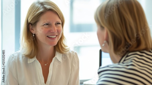 Business meeting between two women discussing strategies in a modern office, emphasizing collaboration, communication, and professional relationship building. photo