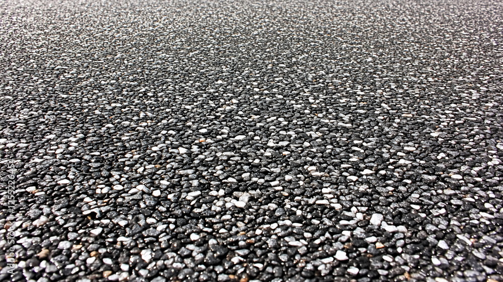Close-Up View of Textured Asphalt Surface with Pebbles and Stones in Various Sizes for Urban Roads