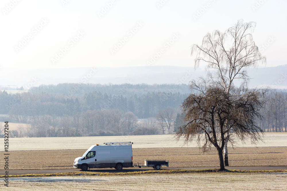 A van drives along a road in the countryside on a cold winter morning