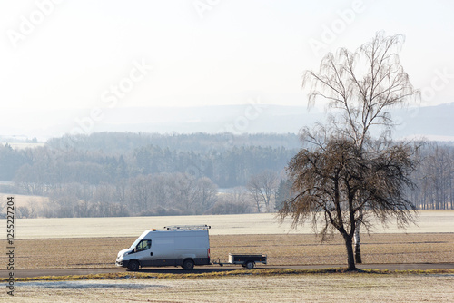Obraz na płótnie A van drives along a road in the countryside on a cold winter morning w salonie