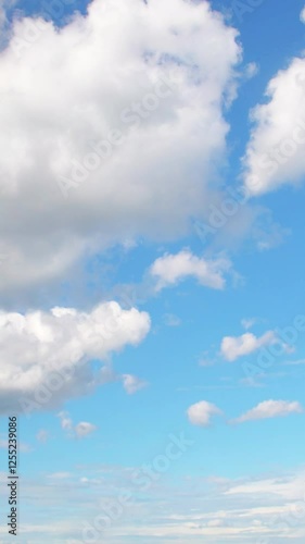 Big white clouds slowly floating across the blue sky. Background with a calm summer sky.