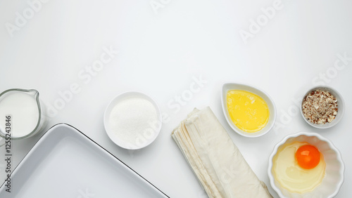 Baking Crinkle Cake. Near baking dish with ingredients, phyllo dough, egg, butter, nuts, and milk photo