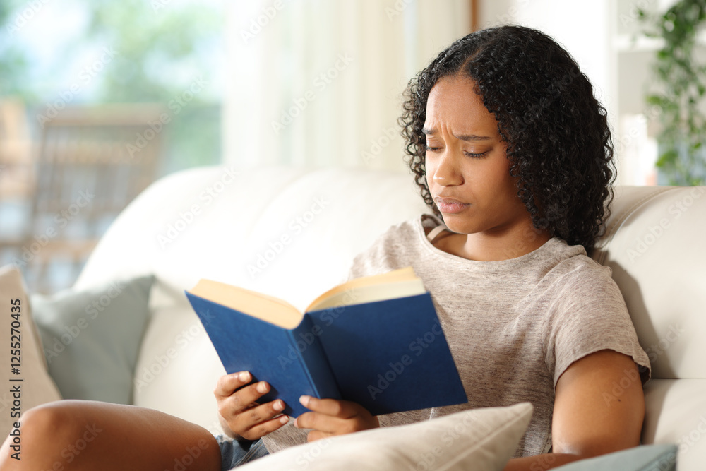 Worried black woman reading a paper book at home Worried black woman reading a paper book at home