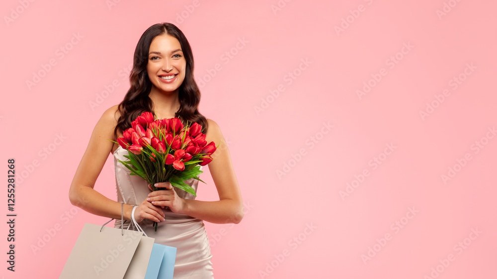 Perfect Women's Day presents. Attractive lady with red tulips bouquet and shopping bags posing over pink background and smiling at camera, free space Perfect Women's Day presents. Attractive lady with red tulips bouquet and shopping bags posing over pink background and smiling at camera, free space