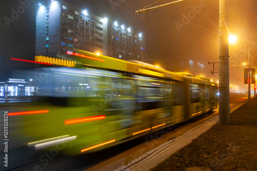 A blurred bus moves along the avenue in the evening. Shot with a long exposure.