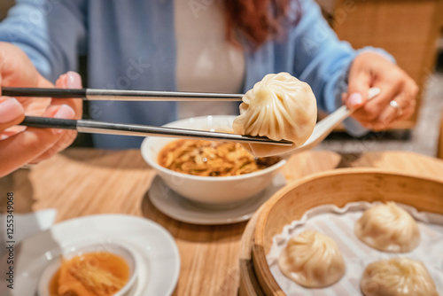 Obraz na płótnie Close up of woman using chopsticks picking up a xiaolongbao dumpling from bamboo steamer basket in a chinese restaurant w salonie