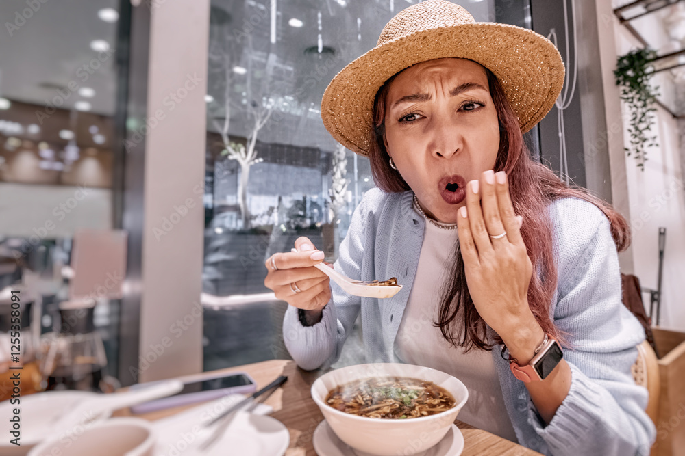 Tourist enjoying traditional food in a chinese restaurant, surprised by the taste of hot and spicy soup