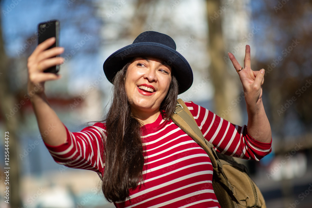 Mature woman taking a selfie and making a peace sign outdoors Mature woman taking a selfie and making a peace sign outdoors