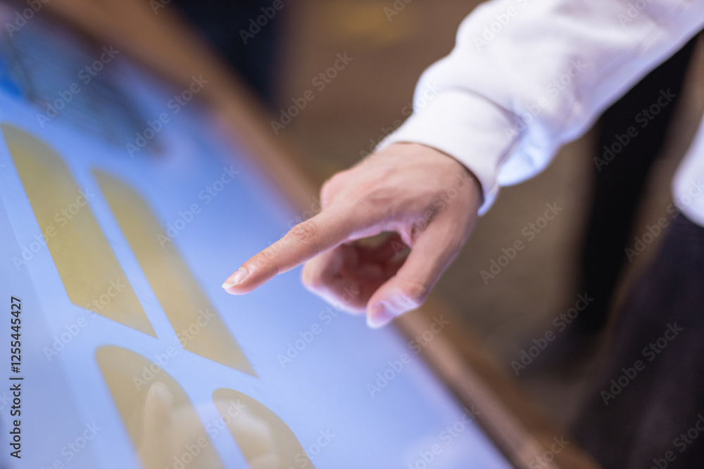 Obraz premium a man uses an interactive touch display at a city exhibition - scrolling and touching. Entertainment and technology concept