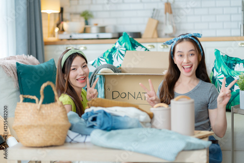 Billede på lærred girl friend sitting pack object,putting on stuff into donate box with second hand clothes at home,Recycling,Donation for poor,asian young woman,charity helping and needy people