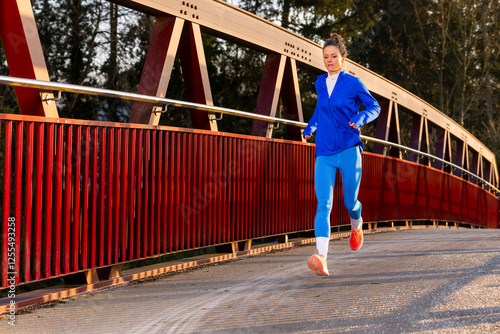 Woman running over a bridge in sportswear during morning exercise photo