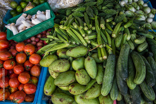 A vivid display of assorted vegetables and fruits fills colorful baskets at a bustling market stall. Bright hues and diverse textures showcase a fresh harvest ready for cooking and culinary inspiratio photo