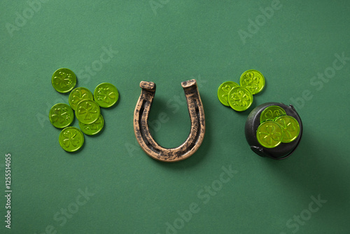 St. Patrick's day composition with green coins, clover leaves and horseshoe on green background. View from above.