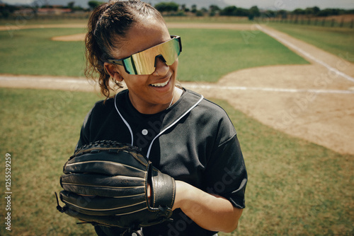 Professional female baseball player wearing sunglasses standing near the baseline with a glove photo