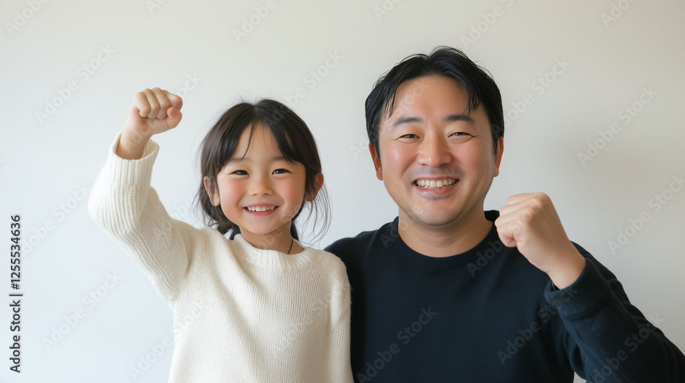 日本人の小学生の娘と40代の父親が笑顔でガッツポーズしているツーショット写真 上半身