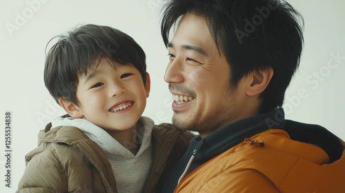 Obraz na płótnie 笑顔の男の子とお父さんが向かい合って抱っこしている スタジオで撮影した記念写真 幼児 小学生 低学年 1年生 w salonie