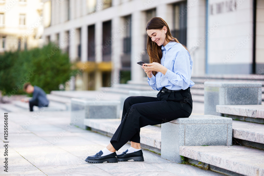 Woman sitting on steps in a city while checking her phone during a sunny afternoon Woman sitting on steps in a city while checking her phone during a sunny afternoon