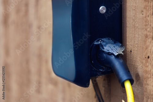 Electrical connection point mounted on a wooden wall with visible wiring in late afternoon light