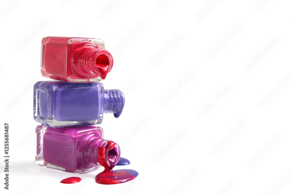 An open pour of three colors of varnish in glass bottles is placed on a white background, stacked. An open pour of three colors of varnish in glass bottles is placed on a white background, stacked.
